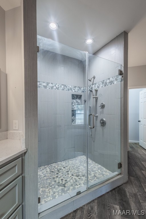 bathroom featuring vanity, hardwood / wood-style flooring, and a shower with door