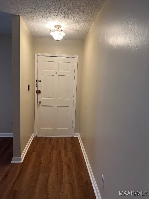 doorway to outside with a textured ceiling and dark hardwood / wood-style flooring