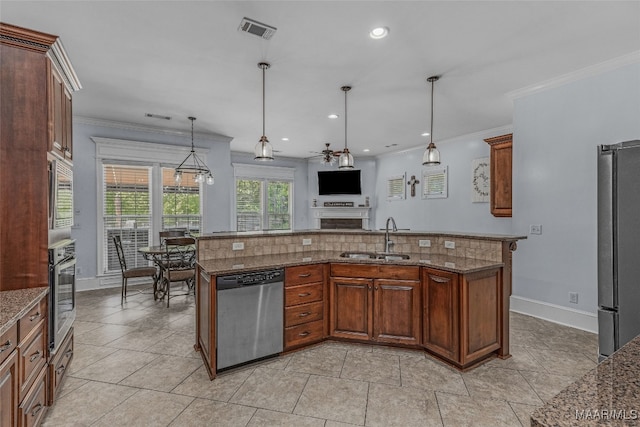 kitchen with stone counters, decorative light fixtures, appliances with stainless steel finishes, sink, and a kitchen island with sink