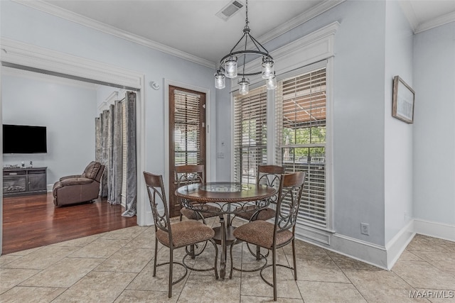 dining space with light wood-type flooring, a chandelier, and ornamental molding