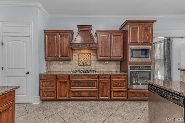 kitchen with dark stone counters, tasteful backsplash, stainless steel appliances, premium range hood, and light tile patterned flooring