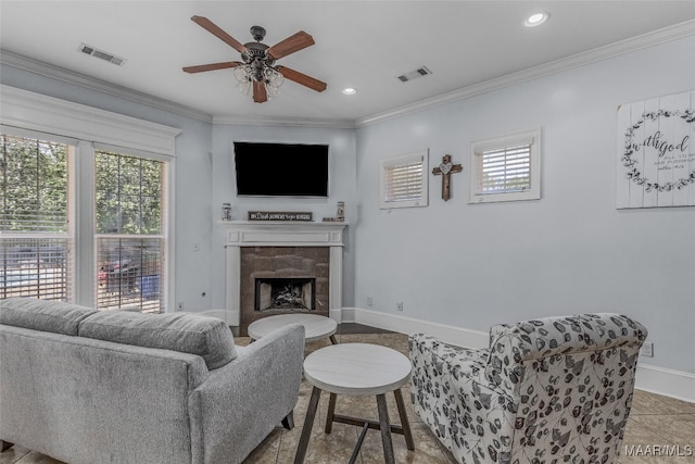 living room with ornamental molding, ceiling fan, and a tile fireplace