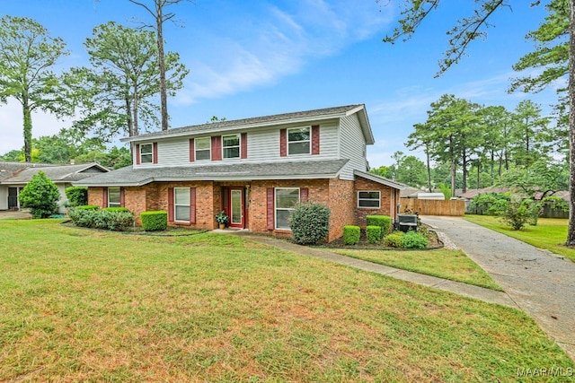 traditional home with a front yard, fence, brick siding, and driveway