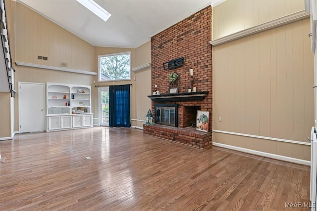 unfurnished living room with a fireplace, wood finished floors, visible vents, and high vaulted ceiling