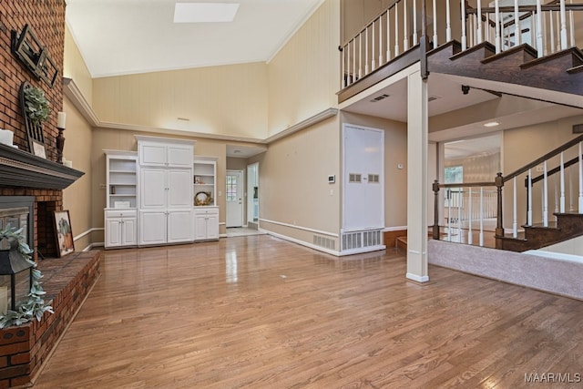 entryway featuring crown molding, a brick fireplace, wood-type flooring, and a towering ceiling