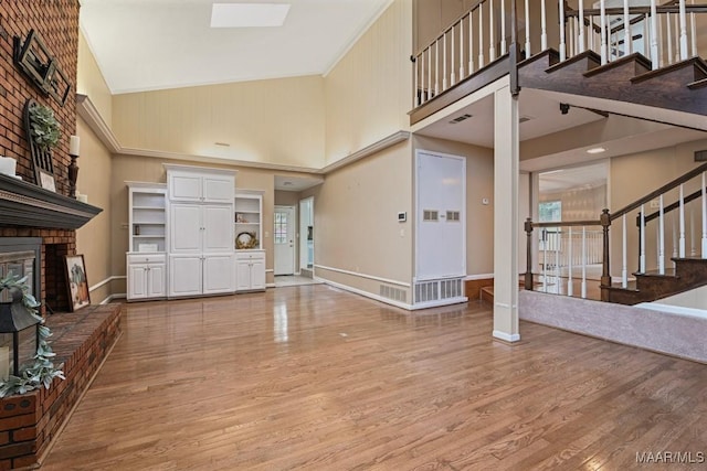 entryway featuring stairs, a towering ceiling, a fireplace, and light wood finished floors