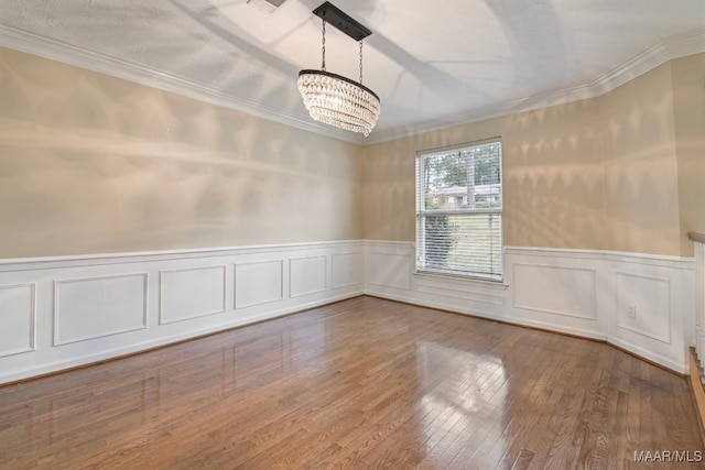 unfurnished room featuring an inviting chandelier, crown molding, and wood-type flooring