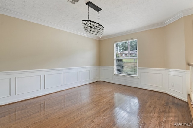 spare room featuring crown molding, hardwood / wood-style floors, a chandelier, and a textured ceiling