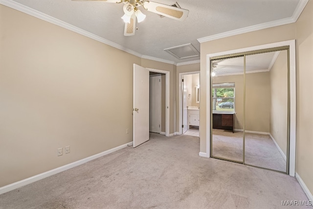 unfurnished bedroom featuring ceiling fan, a textured ceiling, ornamental molding, a closet, and light colored carpet