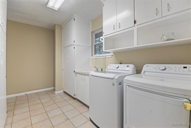 clothes washing area with light tile patterned floors, baseboards, separate washer and dryer, cabinet space, and a sink