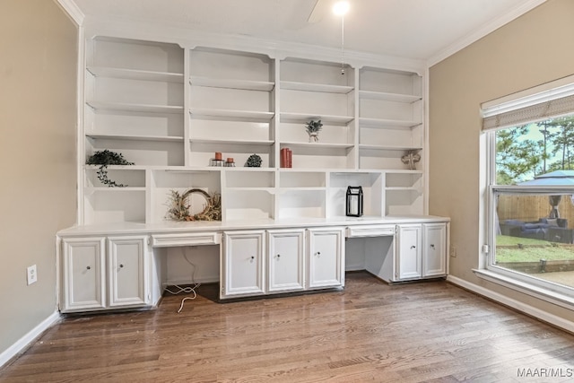 unfurnished office featuring built in desk, crown molding, and dark hardwood / wood-style flooring