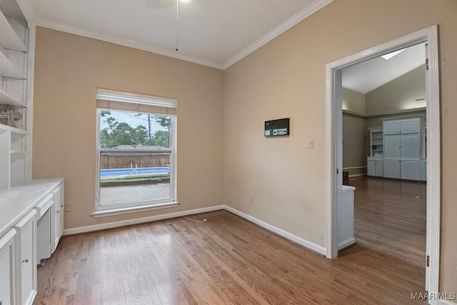 unfurnished dining area with built in shelves, baseboards, light wood-style floors, and ornamental molding