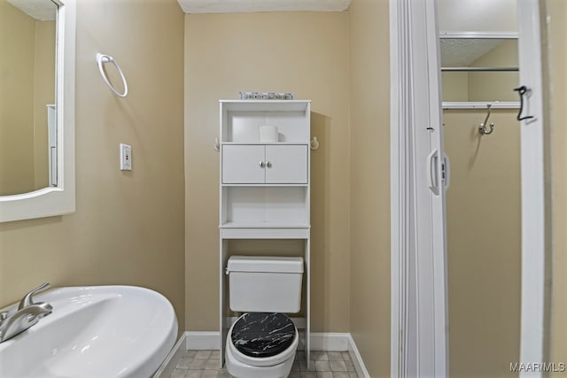 bathroom with toilet, a textured ceiling, sink, and tile patterned floors