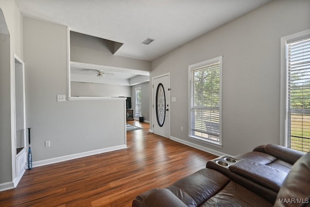 living room with a textured ceiling, ceiling fan, and dark hardwood / wood-style floors