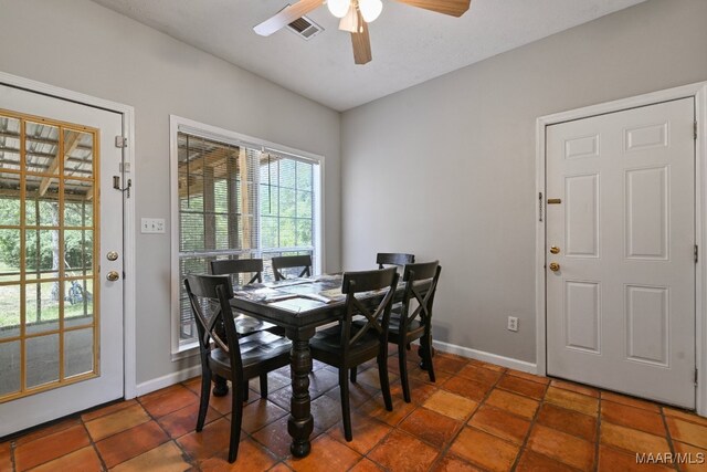 dining area featuring ceiling fan and dark tile patterned flooring