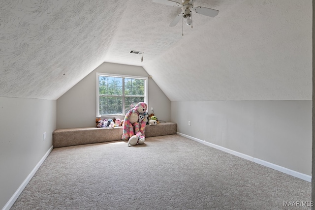 rec room with a textured ceiling, lofted ceiling, ceiling fan, and carpet flooring