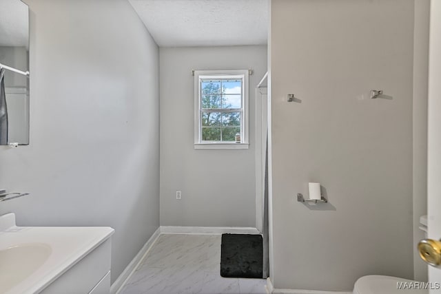 bathroom with a textured ceiling, vanity, and toilet