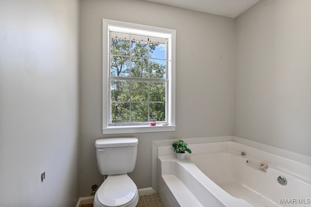 bathroom with tile patterned floors, toilet, a washtub, and a healthy amount of sunlight