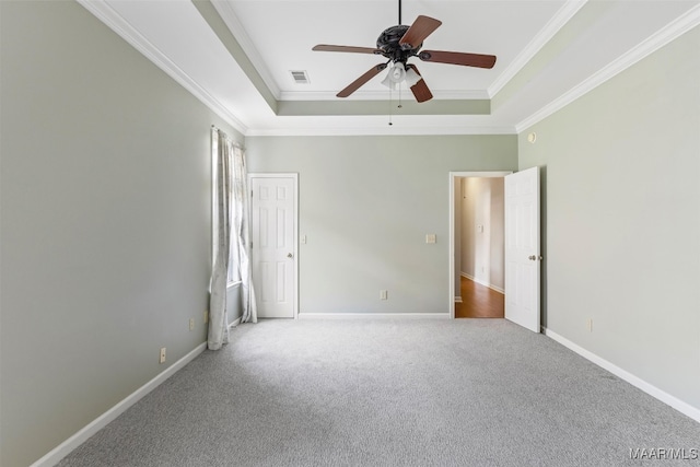 unfurnished bedroom featuring ceiling fan, a raised ceiling, ornamental molding, and carpet