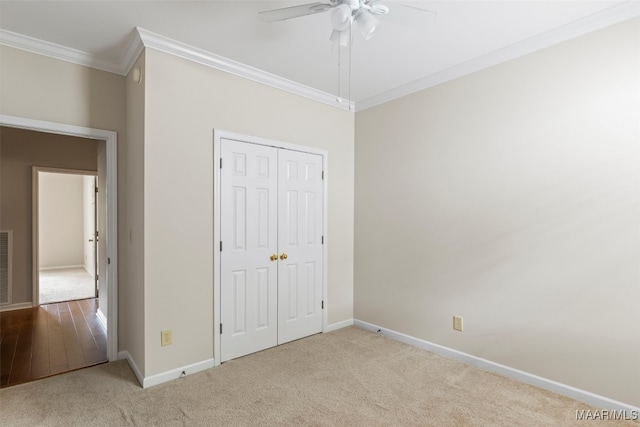 unfurnished bedroom with ornamental molding, a closet, ceiling fan, and light colored carpet