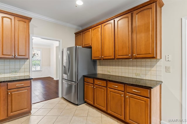 kitchen with dark stone counters, tasteful backsplash, stainless steel fridge with ice dispenser, light hardwood / wood-style flooring, and crown molding