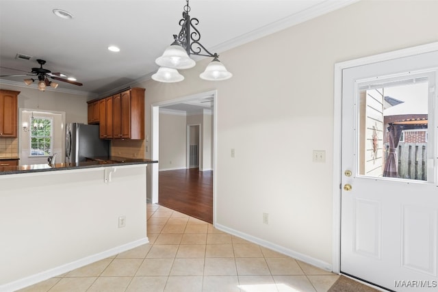 kitchen with stainless steel fridge, backsplash, ceiling fan with notable chandelier, decorative light fixtures, and ornamental molding