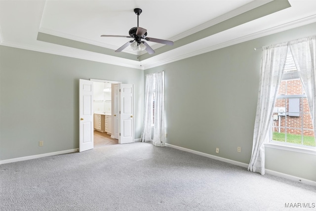 spare room featuring ceiling fan, light colored carpet, a tray ceiling, and ornamental molding