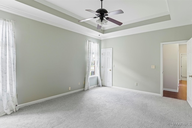 unfurnished bedroom with crown molding, carpet flooring, a tray ceiling, and ceiling fan