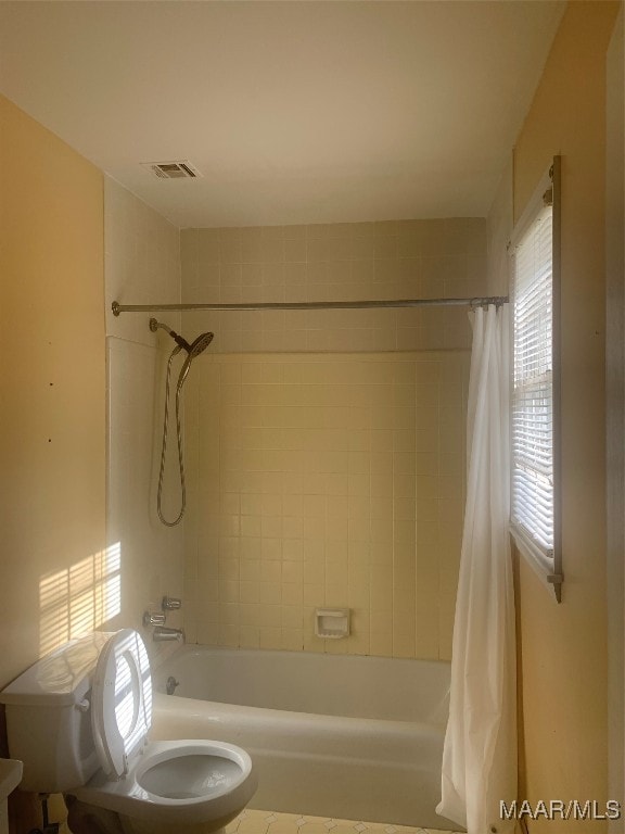 bathroom featuring shower / tub combo with curtain and toilet