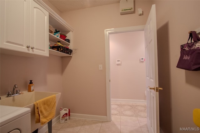 laundry area with a textured ceiling, cabinets, washer / dryer, and light tile patterned floors