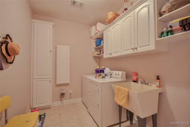 laundry room with a textured ceiling, cabinets, light tile patterned floors, independent washer and dryer, and sink