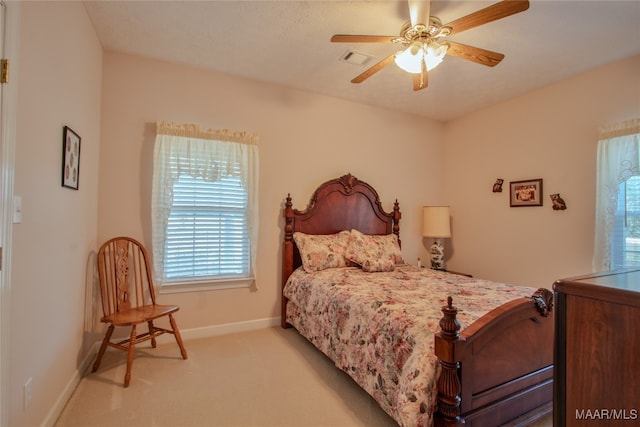 bedroom with multiple windows, ceiling fan, and light colored carpet