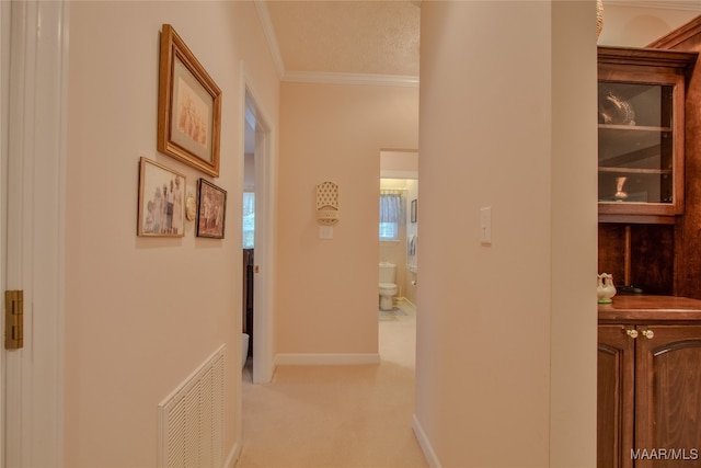 hall with a textured ceiling, ornamental molding, and light carpet