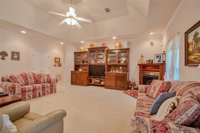 living room featuring ornamental molding, a raised ceiling, ceiling fan, and carpet