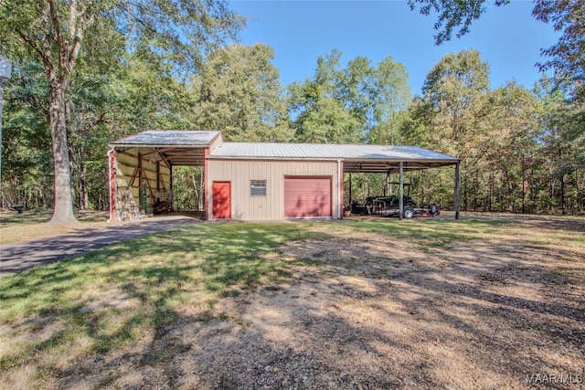 view of outbuilding with a garage, a carport, and a lawn