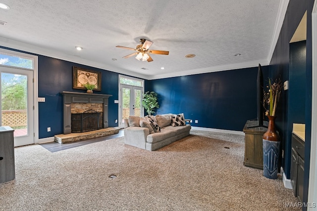 carpeted living room with ceiling fan, french doors, a textured ceiling, a fireplace, and crown molding