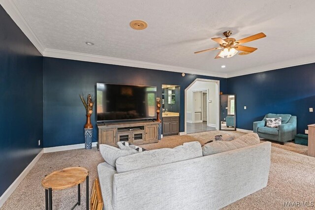 living room featuring ceiling fan, a textured ceiling, carpet floors, and ornamental molding