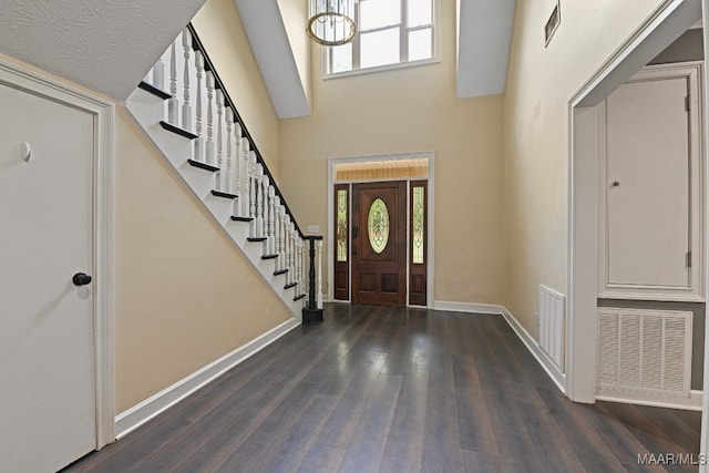 foyer entrance with a high ceiling, a chandelier, a textured ceiling, and dark hardwood / wood-style floors