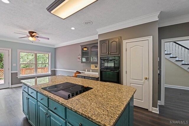 kitchen with dark hardwood / wood-style flooring, black appliances, a center island, ceiling fan, and ornamental molding