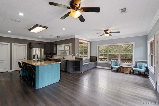 kitchen featuring a kitchen island, dark hardwood / wood-style floors, ceiling fan, and stainless steel appliances