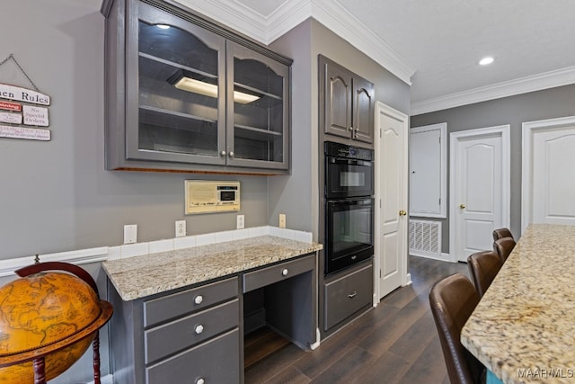 kitchen with dark brown cabinets, built in desk, dark wood-type flooring, a breakfast bar area, and black double oven