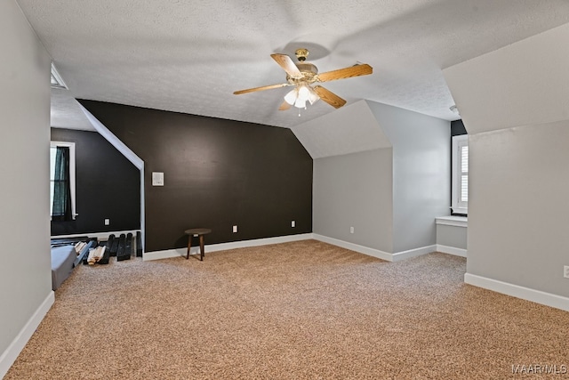 additional living space featuring ceiling fan, light colored carpet, a textured ceiling, and lofted ceiling