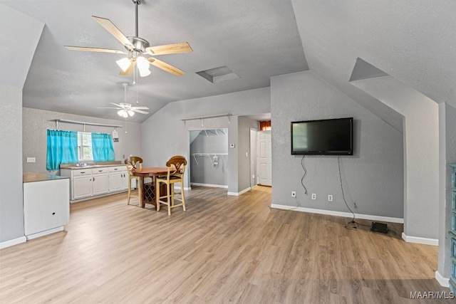 dining room with ceiling fan, lofted ceiling, and light hardwood / wood-style floors