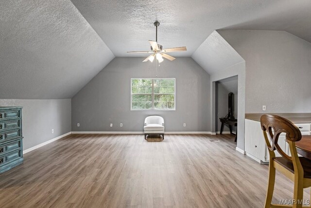 additional living space with lofted ceiling, ceiling fan, hardwood / wood-style flooring, and a textured ceiling