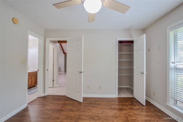 unfurnished bedroom featuring a spacious closet, a closet, ceiling fan, and dark hardwood / wood-style flooring