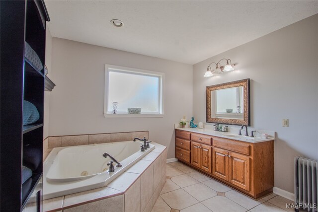 bathroom featuring vanity, tile patterned flooring, tiled bath, and radiator