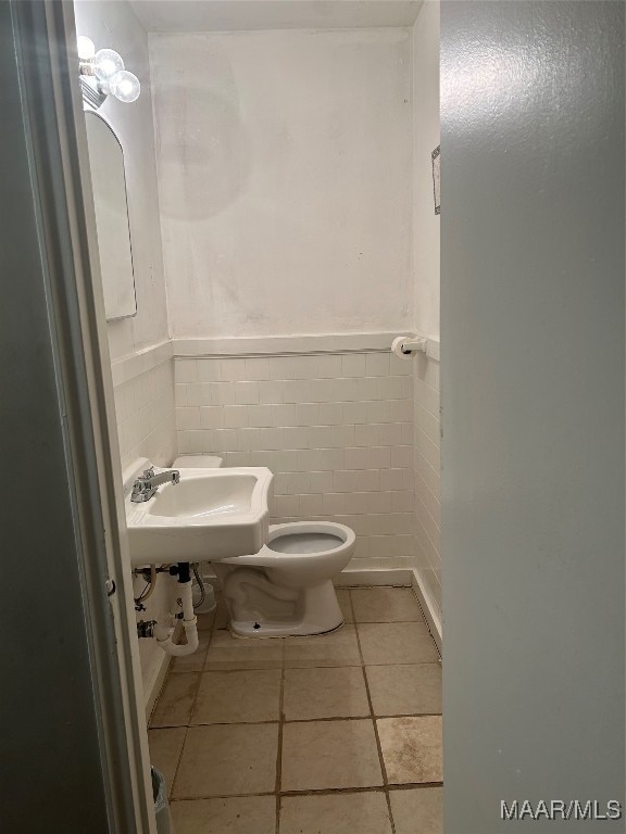 bathroom with tile walls, tile patterned flooring, toilet, and sink