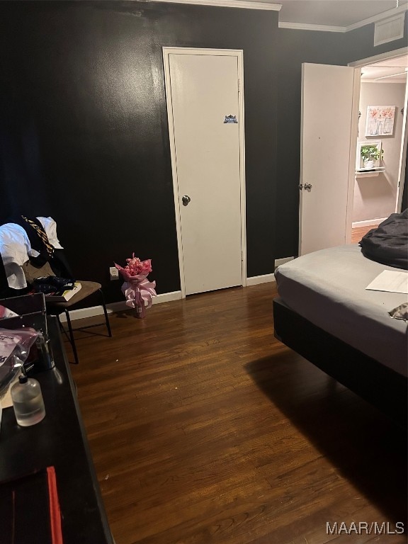 bedroom with ornamental molding and dark hardwood / wood-style floors