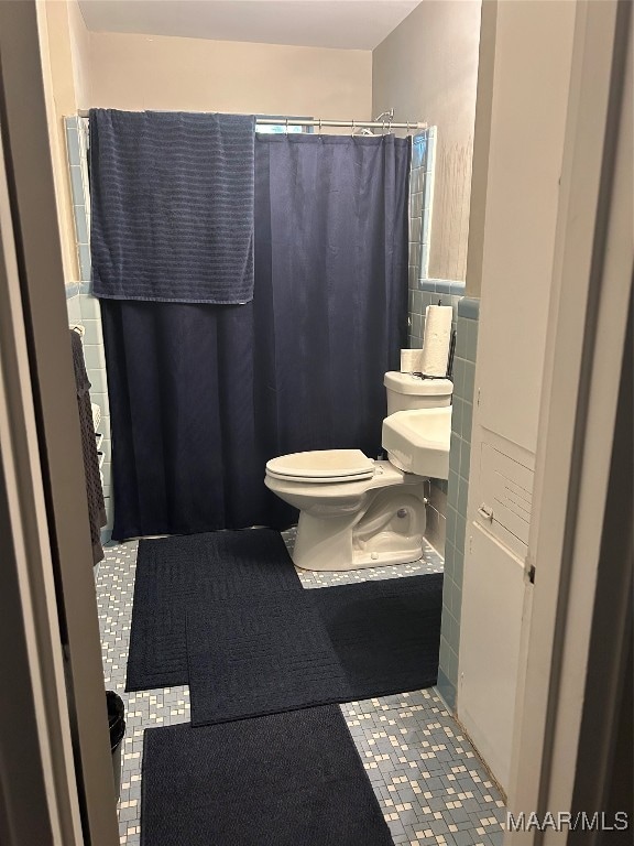 bathroom with curtained shower, toilet, and tile patterned floors