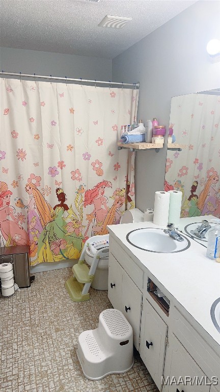 bathroom with vanity, toilet, and a textured ceiling